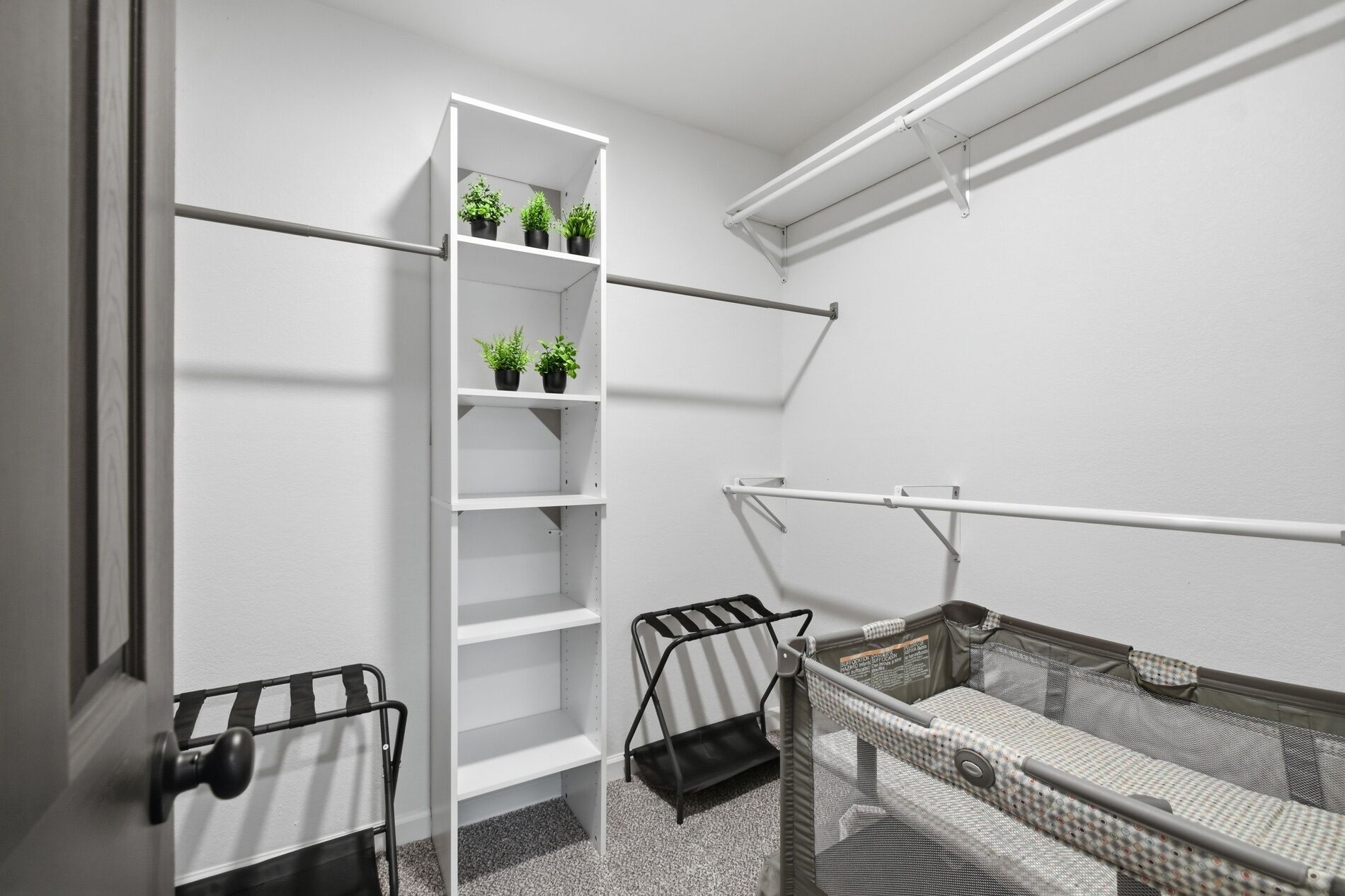 A compact room with a white shelving unit, a black metal rack, and a mesh safety barrier.