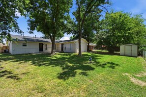 Ein eingeschossiges Haus mit Vorgarten, Garage und Gartenhaus.