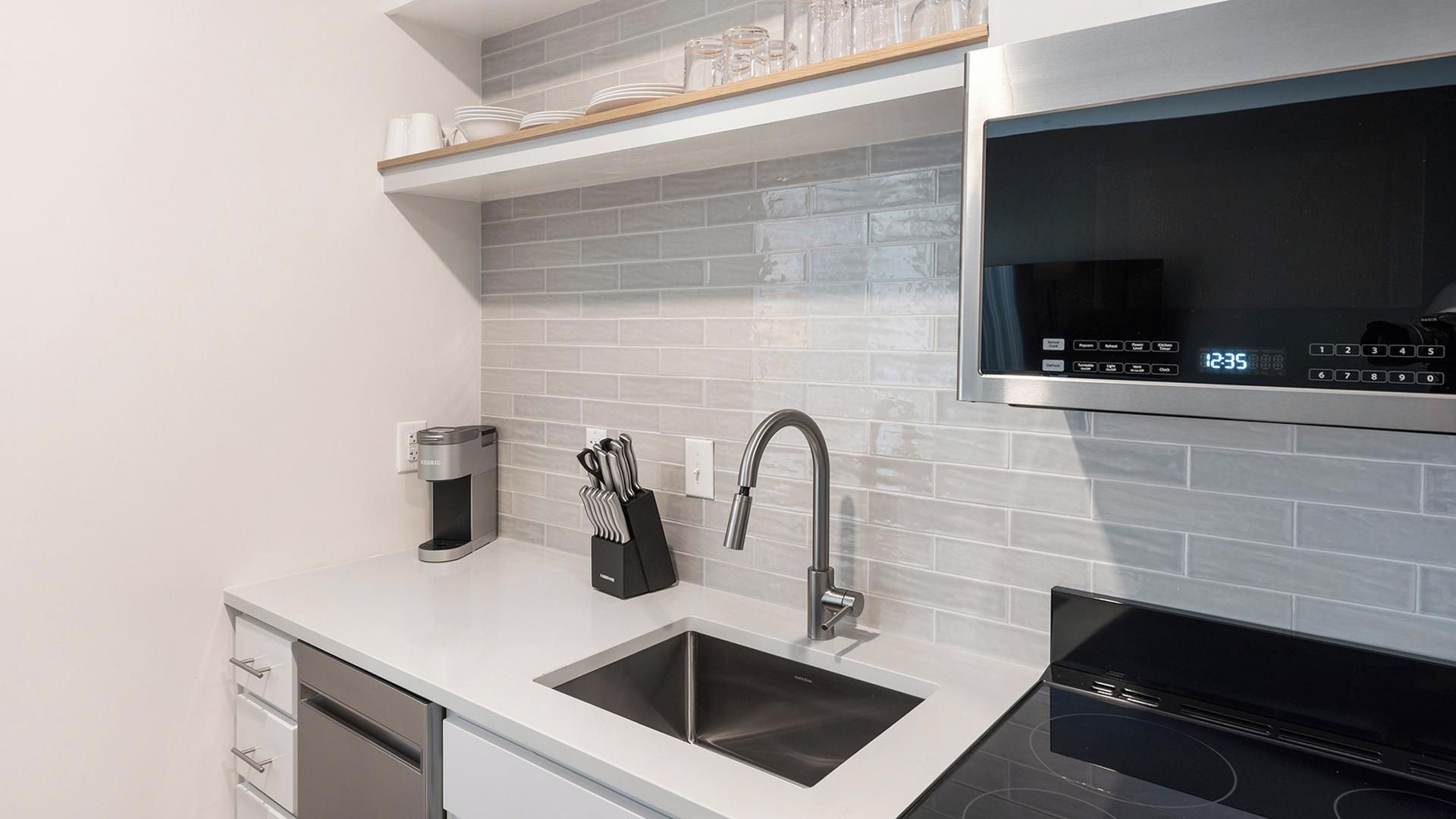 A modern kitchen with a stainless steel sink, a coffee maker, and a microwave.