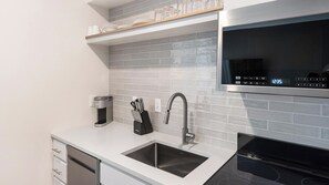 A modern kitchen with a stainless steel sink, a coffee maker, and a microwave. - Landing | Spectacular 1BD in Kannapolis (Kannapolis)