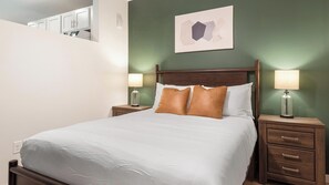 A hotel room with a bed, two bedside tables with lamps, a wall-mounted artwork, and a partial view of a bathroom. - Landing | Spectacular 1BD in Kannapolis (Kannapolis)