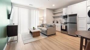 A modern kitchen with white cabinets, a stainless steel refrigerator, and a built-in oven. - Landing | Spectacular 1BD in Kannapolis (Kannapolis)