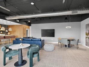 A modern interior with a sectional sofa, round tables, and a flat-screen TV. - Landing | Stylish Studio in Kannapolis (Kannapolis)