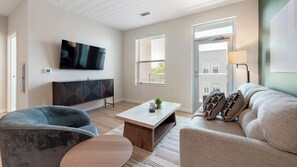 A modern living room with a flat-screen TV, a sofa, a coffee table, and a side table with a plant. - Landing | Modern 1BD in Kannapolis (Kannapolis)