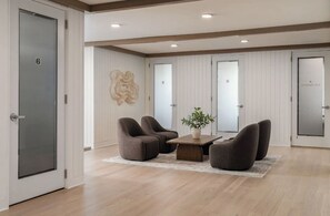 A modern office space with a wooden floor, a central table with chairs, and a decorative wall piece. - Landing | Spectacular 1BD, Pool, Gym (Port Charlotte)