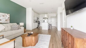A modern living room with a sofa, coffee table, and artwork on the wall. - Landing | Stylish 1BD, Gym, Pool (Port Charlotte)