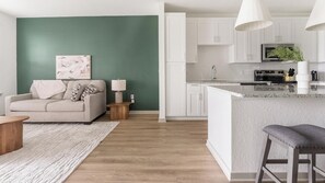 Eine moderne Küche mit weißen Schränken, einem Edelstahlkühlschrank und einer Mikrowelle.