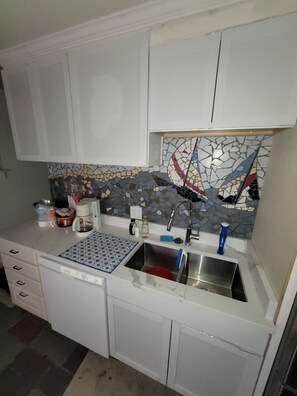 A kitchen with white cabinets, a tiled backsplash, a sink, and a coffee maker. - Charming 3-bedroom house in marvelous Township of Burtchville with AC (Township of Burtchville)