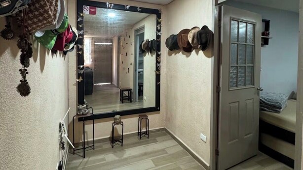 A room with a large mirror, a wooden floor, a door, and a bed. - Orchid House (Cancún)