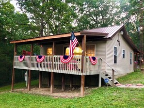 A wooden cabin with a porch decorated with American flags and bunting.