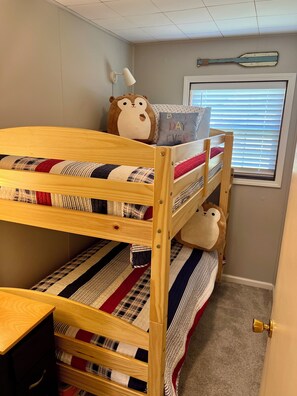 A bunk bed with striped bedding, a lamp, and a window with blinds.
