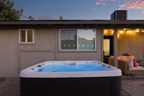 A hot tub in front of a building with a window and a covered patio area with seating. - The ONLY FREE-Heated Pool + Hot Tub + Game Lounge Combo — 10 Min to Old Town (Scottsdale)