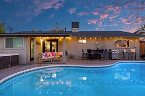 Ein Garten mit Swimmingpool, Grillplatz und einer Sitzgelegenheit mit Sofa und Sesseln.