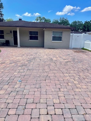A residential house with a paved driveway, a garage door, and a fenced yard. - West Tampa Villas # 3 Near Stadium & Airport And Pool (Tampa)