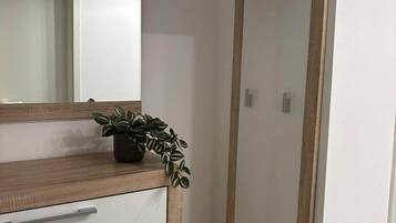 Une salle de bain avec un meuble-lavabo en bois, un miroir, une plante en pot et une étagère verticale.