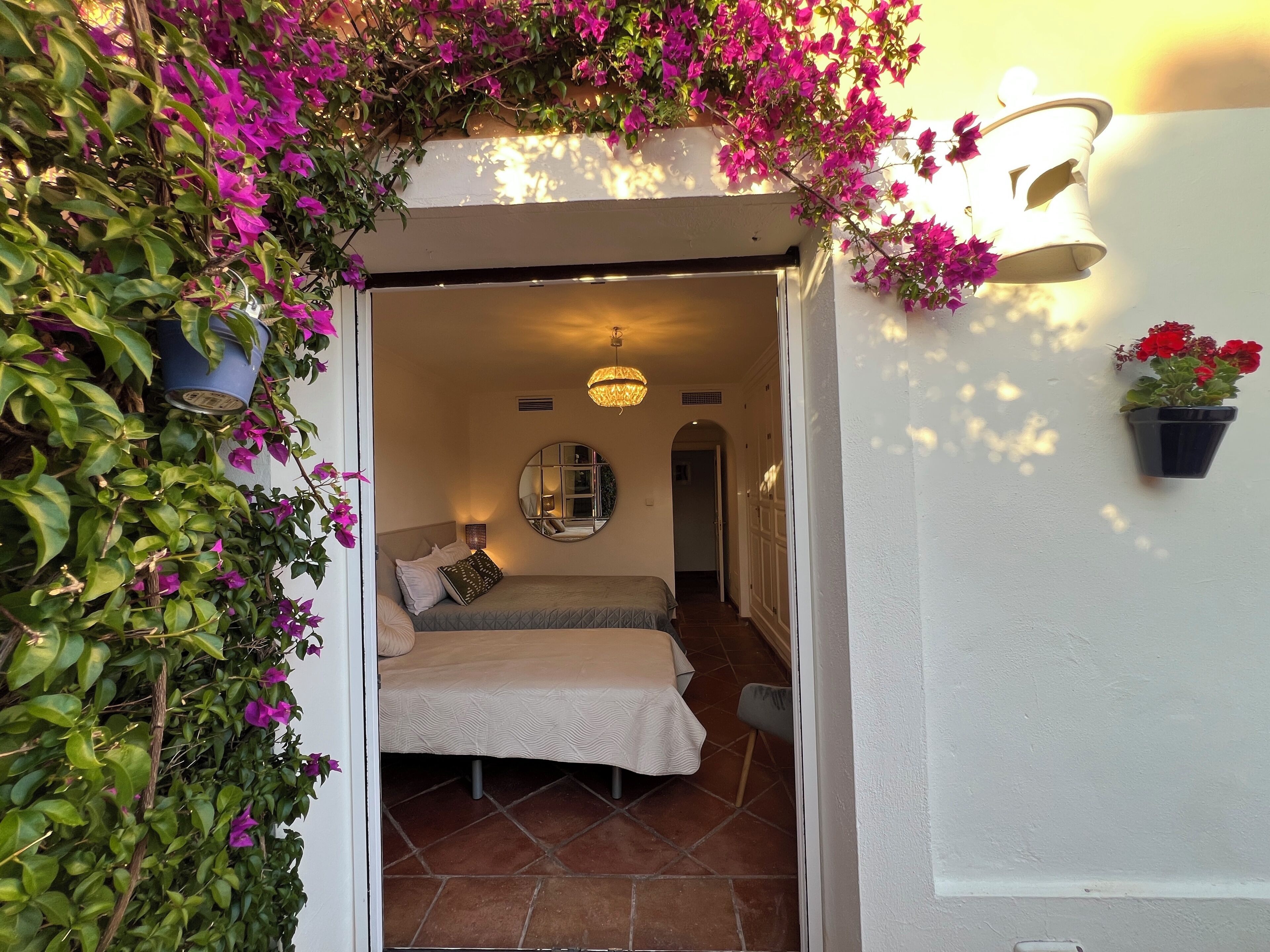 An interior room with a bed, a mirror, and a potted plant.