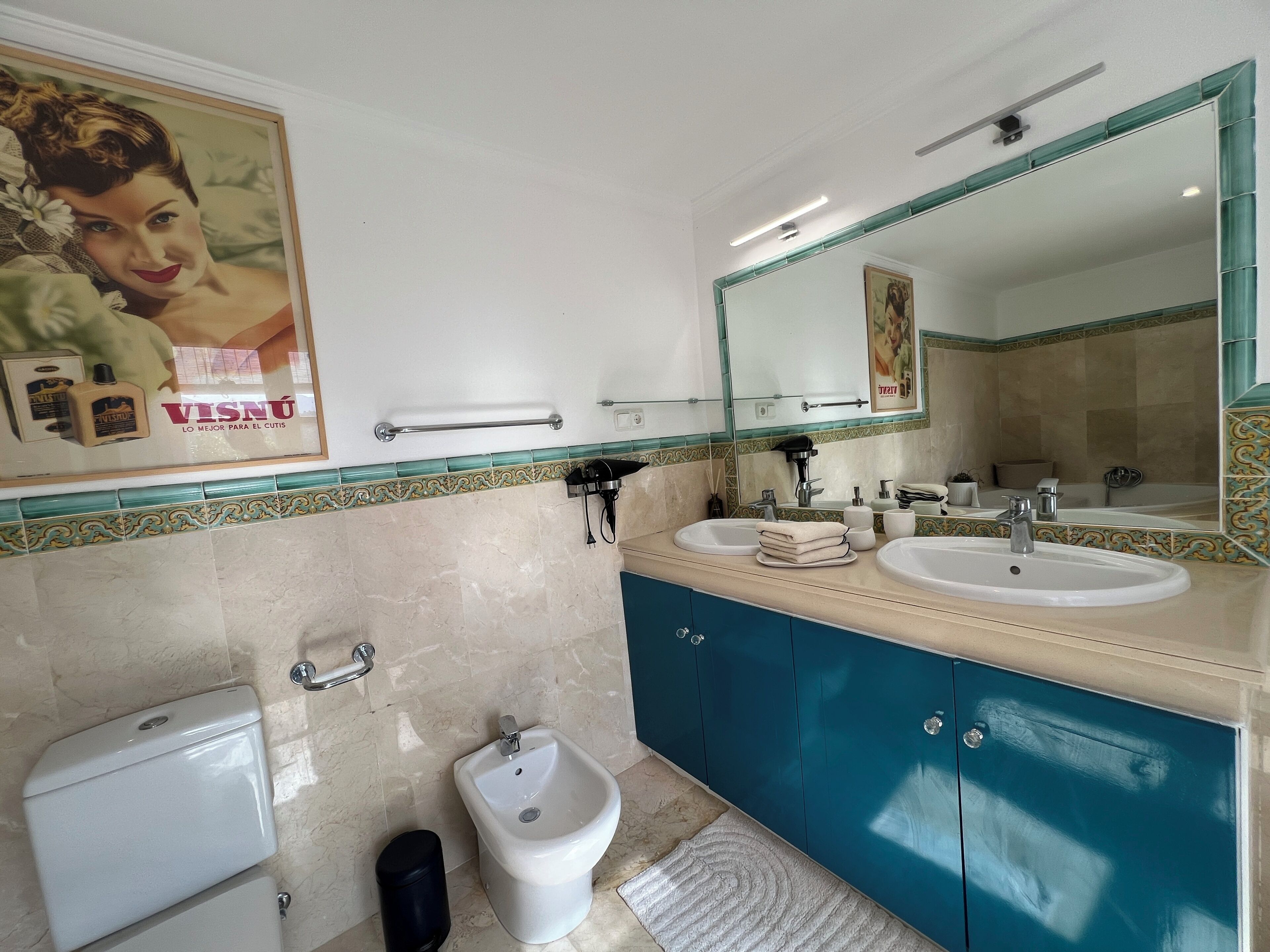 A bathroom with two sinks, a bidet, a toilet, and a large mirror.