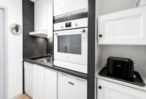 Eine moderne Küche mit weißen Schränken, einem eingebauten Backofen, einem Geschirrspüler und einem Toaster.
