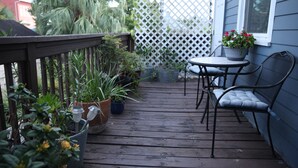 A wooden deck with potted plants, a table, and a chair. - Historic 1 Bedroom Apartment in Marigny Neighborhood next to French Quarter (New Orleans)