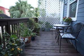A wooden deck with potted plants, a table, and a chair. - Historic 1 Bedroom Apartment in Marigny Neighborhood next to French Quarter (New Orleans)