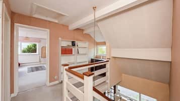 Une pièce avec un plafond en pente, un escalier en bois et une vue sur l’extérieur.