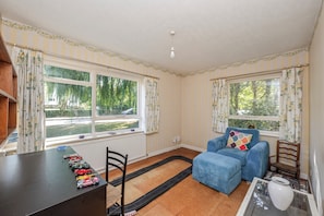 A room with a dining table, chairs, a blue sofa, and a window with curtains.