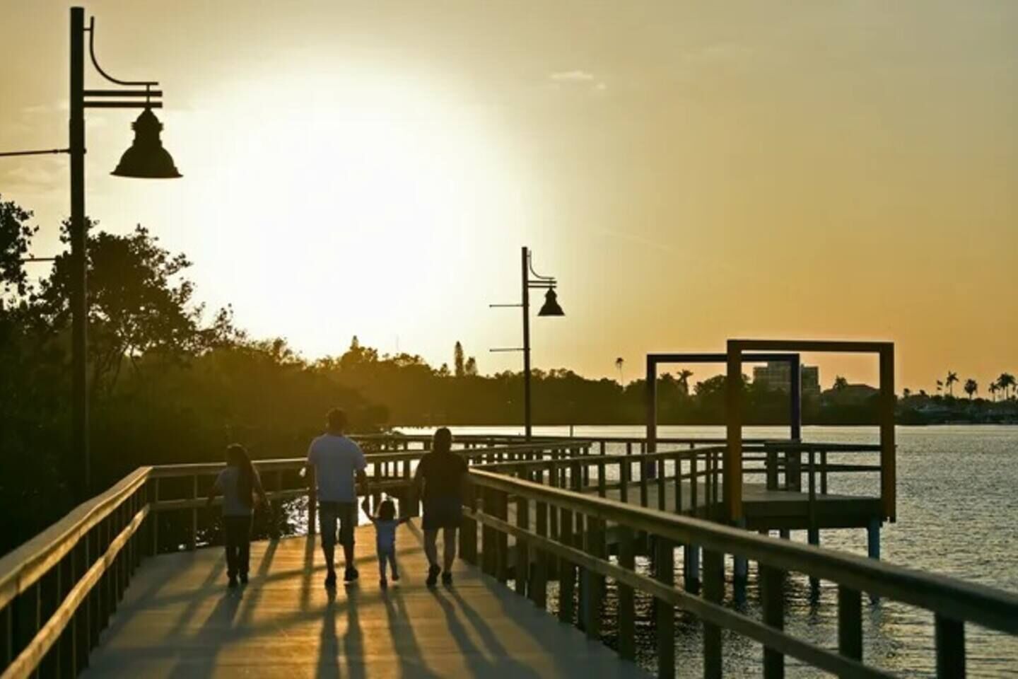 A wooden pier with railings, a lamp post, and a view of the water.