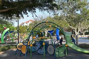 Ein Spielplatz im Freien mit verschiedenen Spielgeräten, darunter eine Rutsche und Kletterelemente.