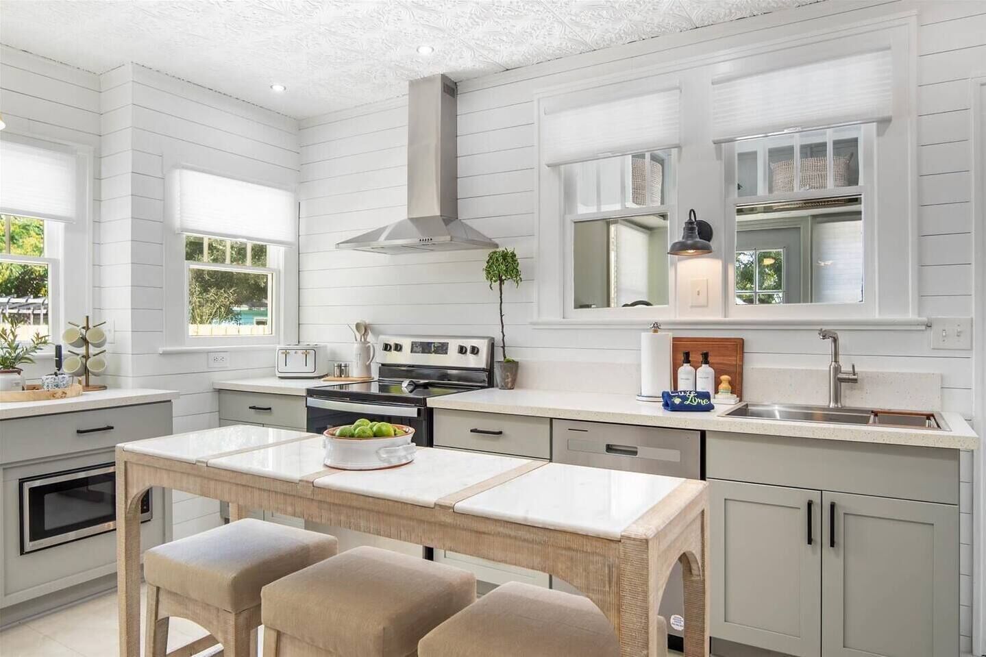 Guests can enjoy this fully stocked kitchen by cooking with ease using stainless steel appliances and ample counter space; gathering at the central island, and soaking in the bright, inviting atmosphere.