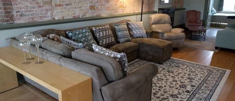 A living room with a sectional sofa, a wooden coffee table, and a patterned rug.