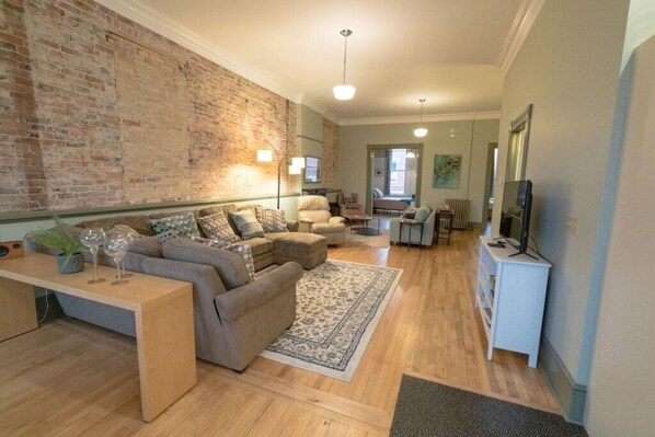 A living room with a brick wall, a sofa, a coffee table, and a television.