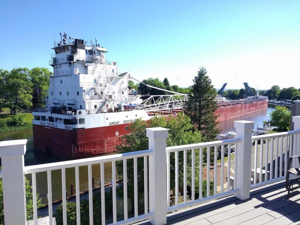 A large cargo ship docked at a port with a white railing in the foreground.