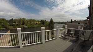 Una terraza con barandilla blanca, con vista a un río y follaje.