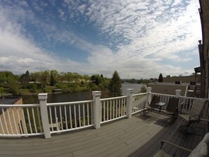 Eine Terrasse mit weißer Reling, mit Blick auf einen Fluss und Grünflächen.