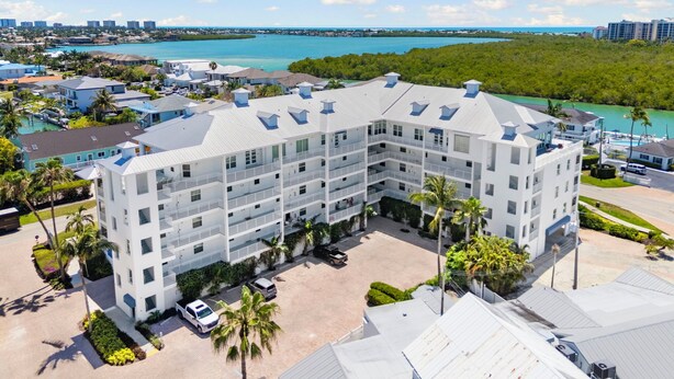 A multi-story hotel with a central courtyard, surrounded by lush greenery and a view of the ocean.