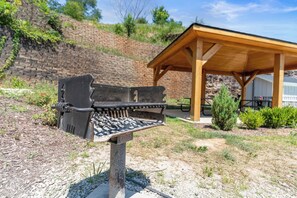 Uma pérgola de madeira com grelha de metal numa área ajardinada.