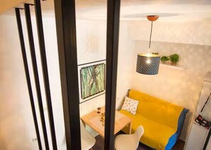 A room with a yellow sofa, a small table, and a hanging light fixture. - Central Old town house with courtyard & Beach walk (Split)