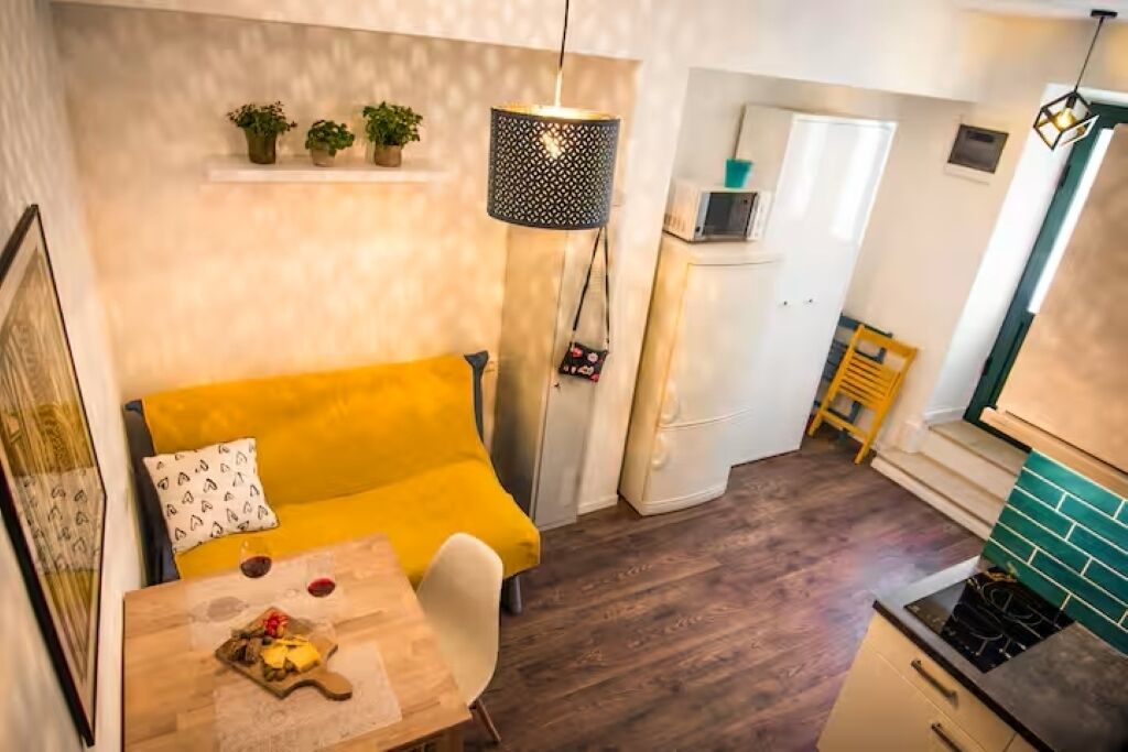 A compact living space with a sofa, a dining table with a plate of food, a refrigerator, and a microwave.