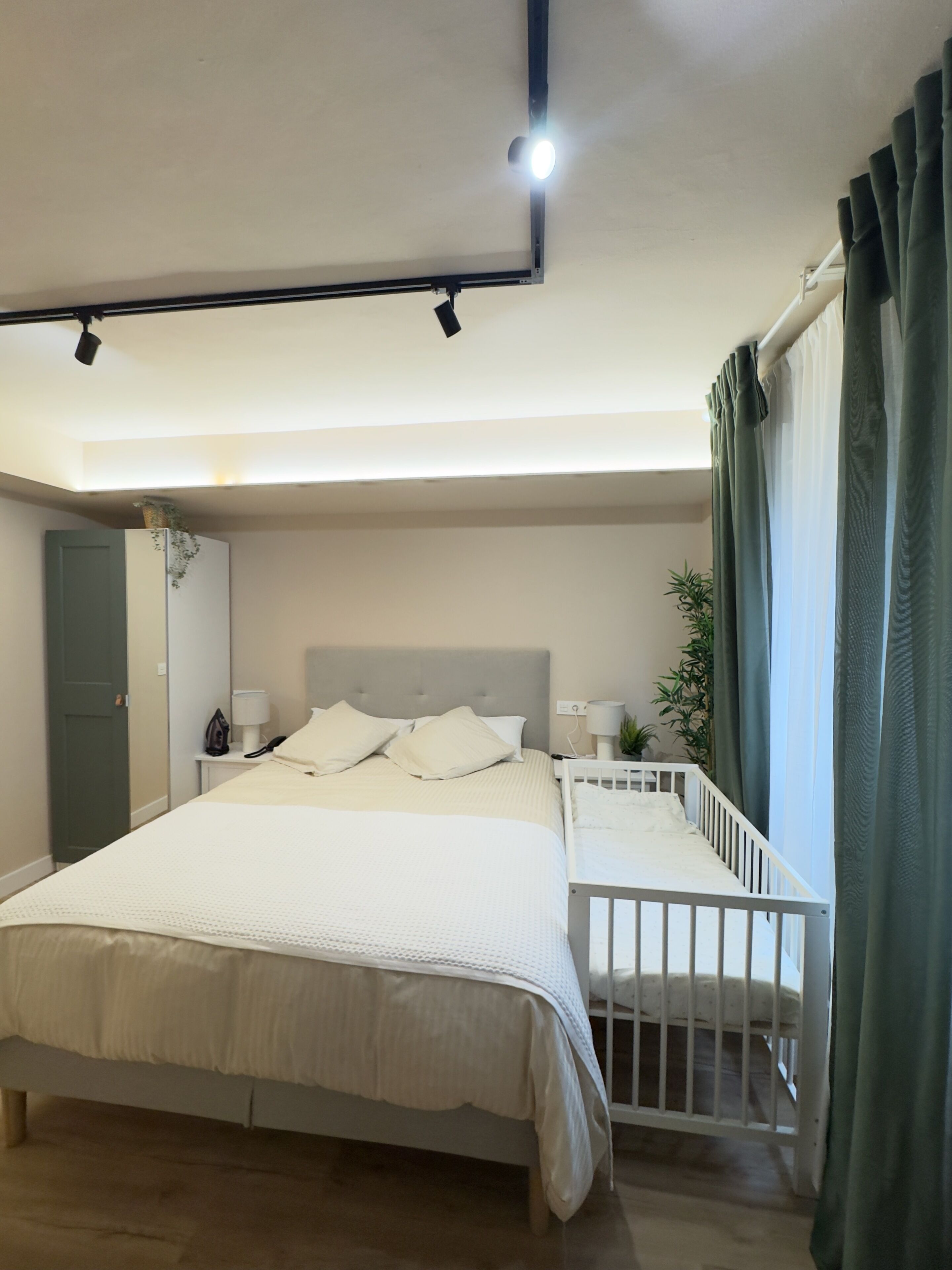 Une chambre à coucher avec un lit, des tables de chevet, une commode, une fenêtre avec des rideaux et une porte.