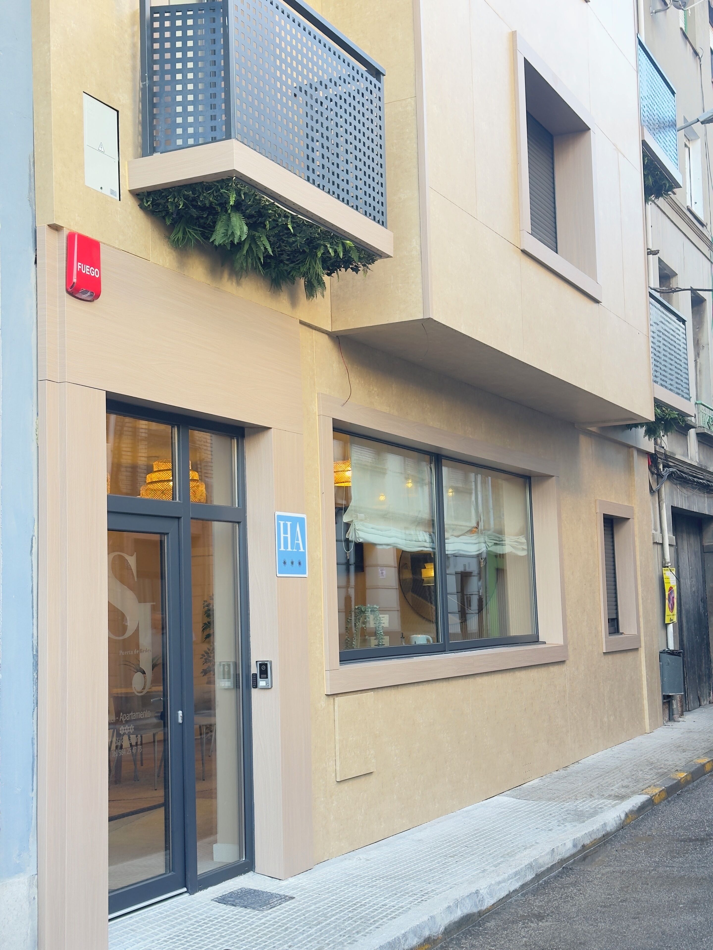 Un edificio con entrada a nivel de calle, detector de incendios visible y un cartel que indica un hotel.