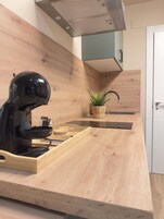 Una cocina moderna con cafetera integrada, encimera de madera y una pequeña planta en maceta.
