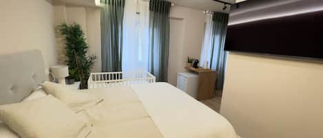 Une chambre à coucher comprenant un lit, une table de chevet, une lampe, une plante en pot et un petit bureau avec une chaise.