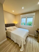 Un dormitorio con cama, mesita de noche y ventana con vistas.