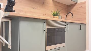 Una cocina con horno empotrado, campana extractora de acero inoxidable y encimera de madera.