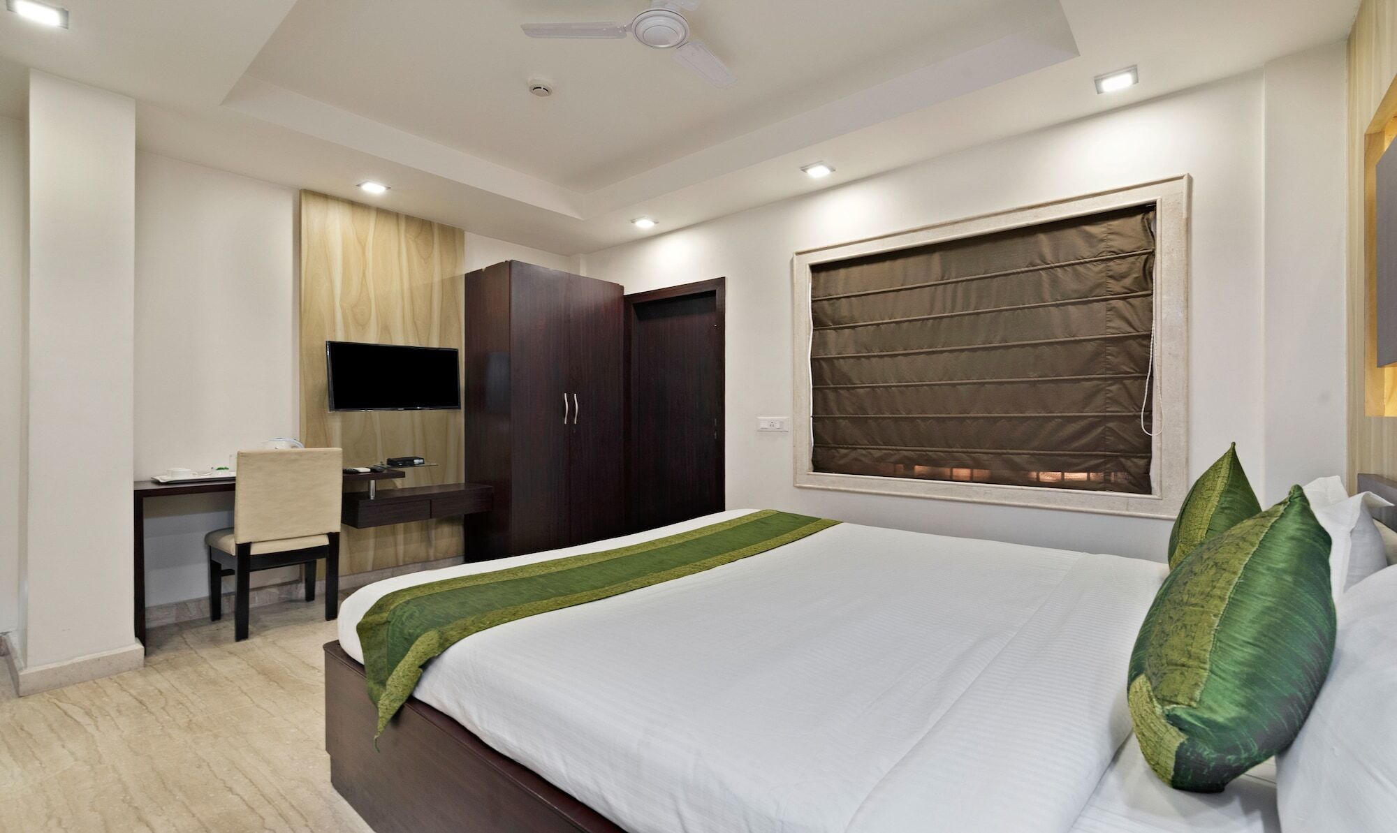 A hotel room with a bed, a desk, a television, and a wardrobe.