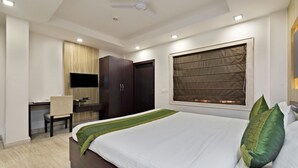 Een hotelkamer met een bed, een bureau, een televisie en een kledingkast.
