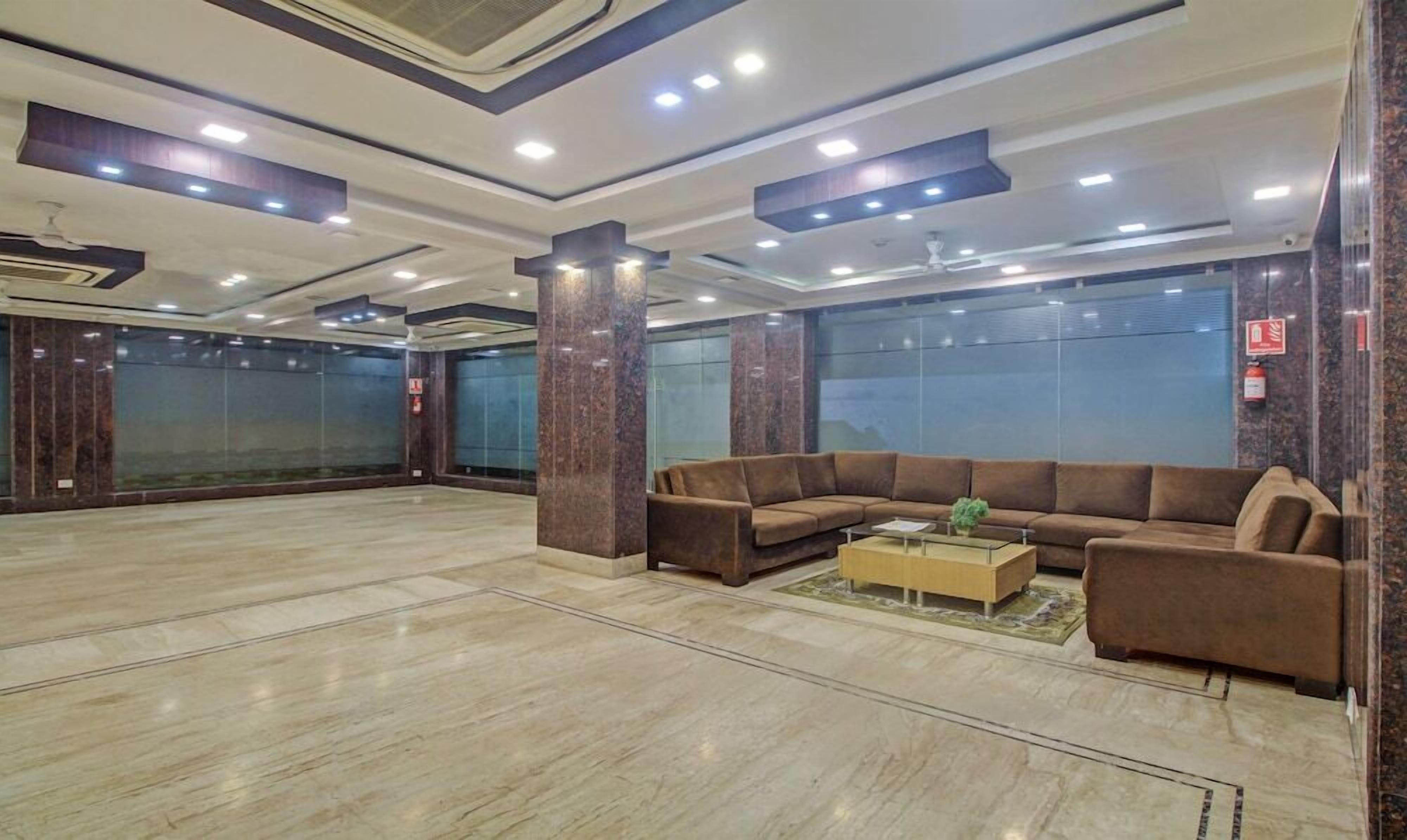 A spacious lobby with a large brown sofa, a coffee table, and a marble floor.