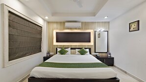 Een hotelkamer met een bed, een grote spiegel, een airconditioning en een plafondventilator.