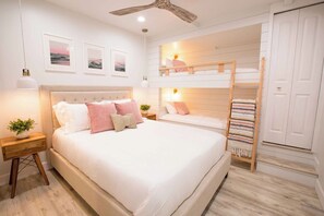Quarto com uma cama beliche, mesa de cabeceira com luminária e prateleira na parede.