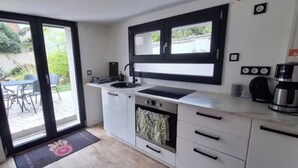 Una cocina moderna con horno empotrado, cafetera y ventana sobre el fregadero.